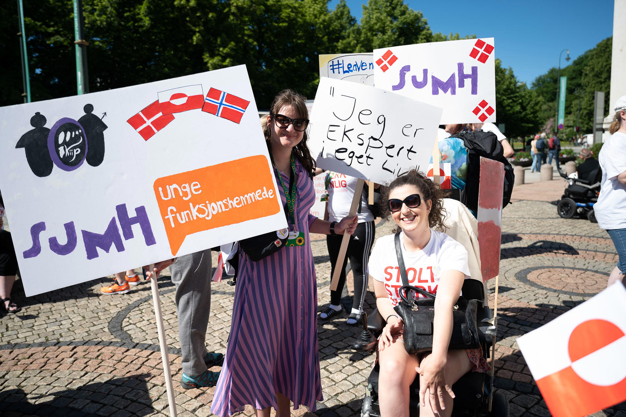 To unge kvinder som deltager i Disability Pride paraden i Oslo i 2022. Den ene holder et skilt hvor der står: "Jeg er ekspert i eget liv"