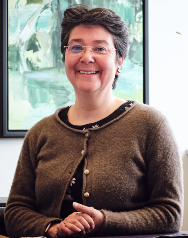 Ældretalsmanden i en brun cardigan der smiler.