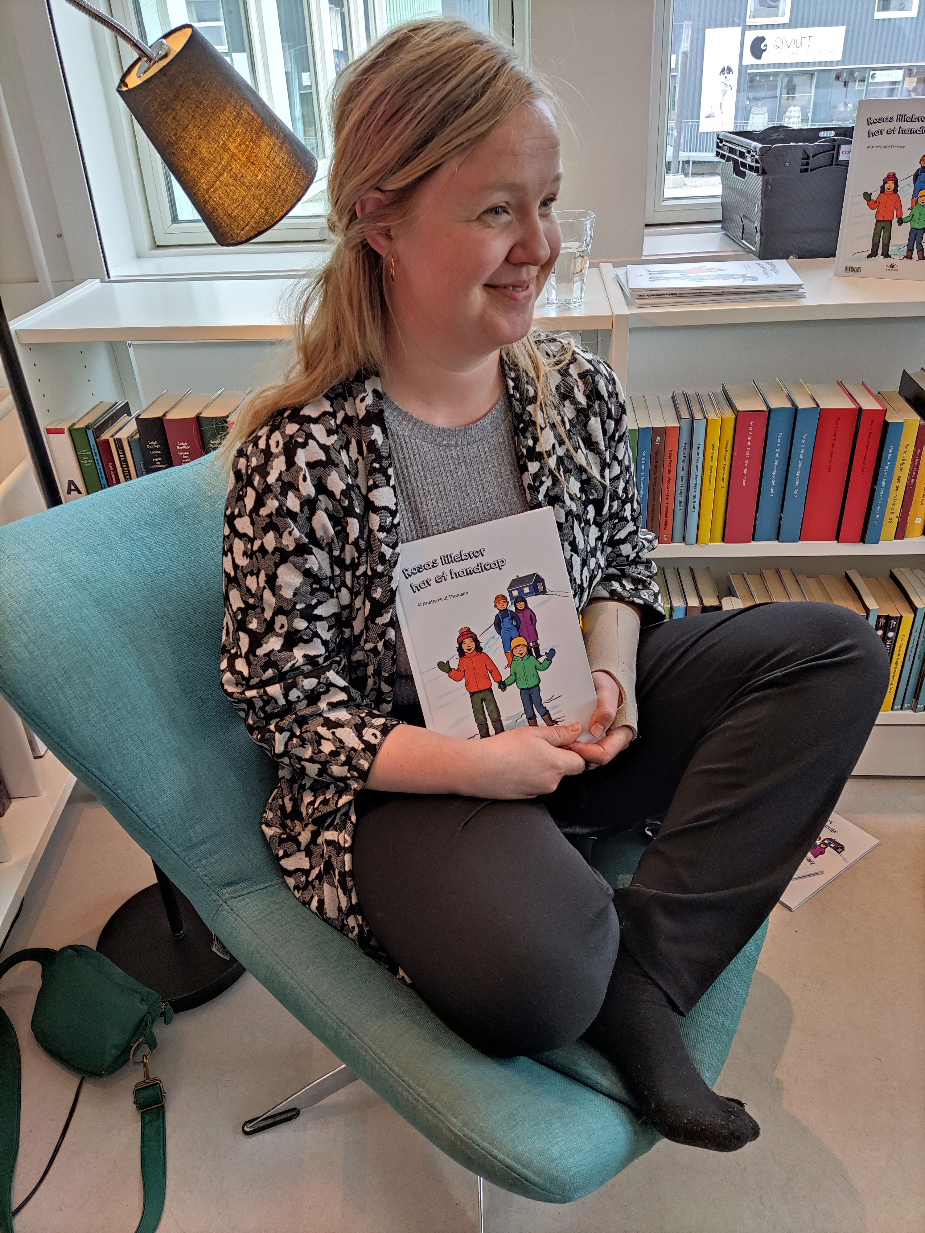 Tilioqs medarbejder Anna Ida sidder med bogen Rosas lillebror har et handicap, til en oplæsning af bogen.